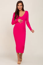 Fuchsia fitted maternity maxi dress with a v-neckline and long sleeves worn by a pregnant woman