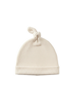 Soft cream waffle knit knot hat for newborns, featuring a tied top and gentle texture.