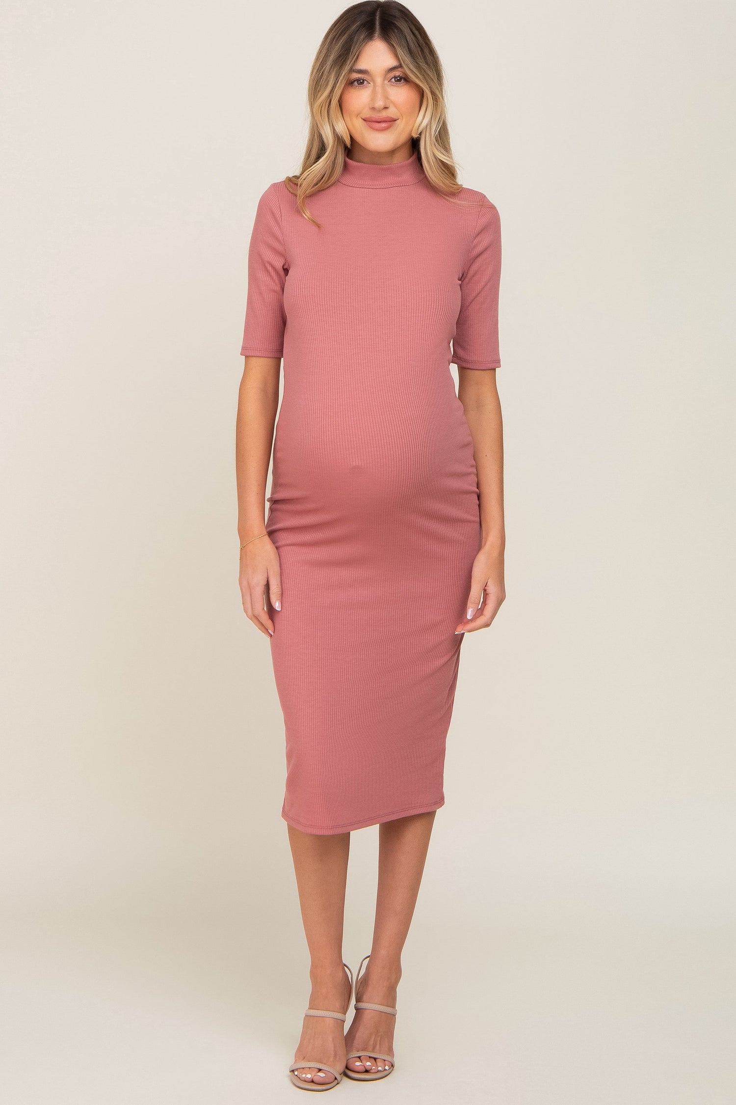 Mauve ribbed maternity midi dress with a mock neck and short sleeves on a pregnant woman.