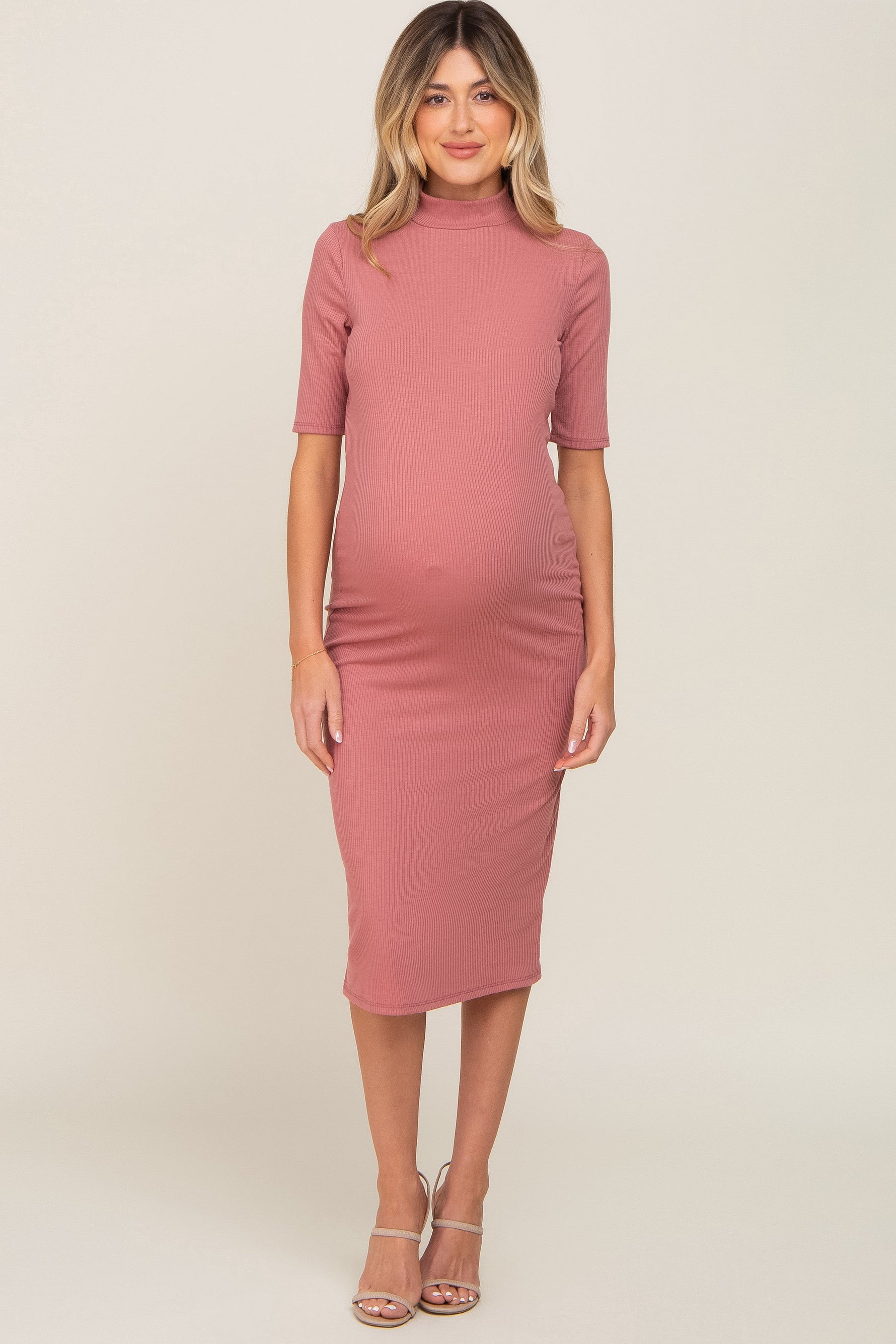 Mauve ribbed maternity midi dress with a mock neck and short sleeves on a pregnant woman.