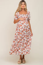 Full-length view of a pregnant woman in a cream floral smocked square neck tiered maternity maxi dress.