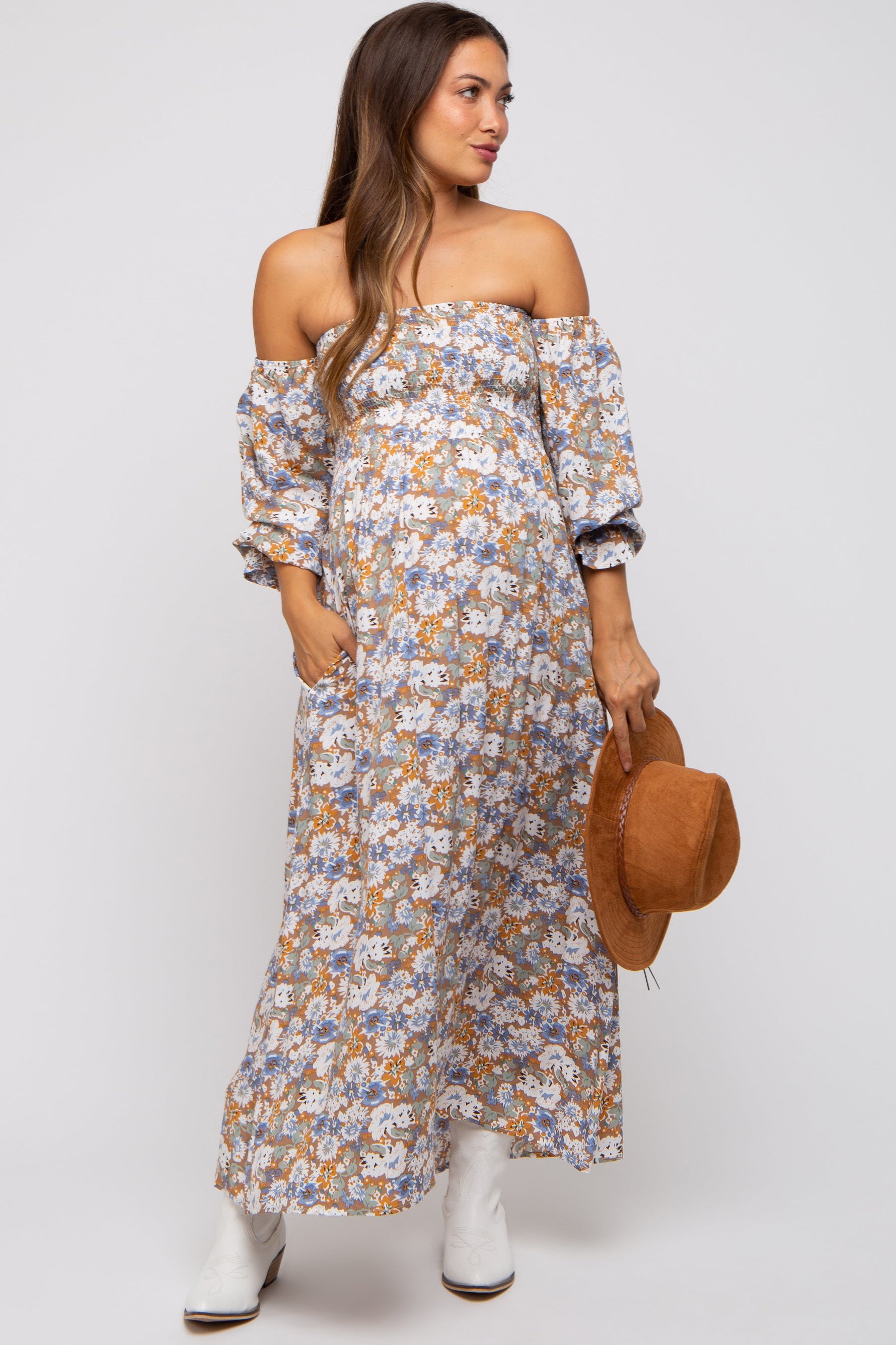 Pregnant woman wearing a taupe floral print off-shoulder smocked maternity maxi dress, smiling.