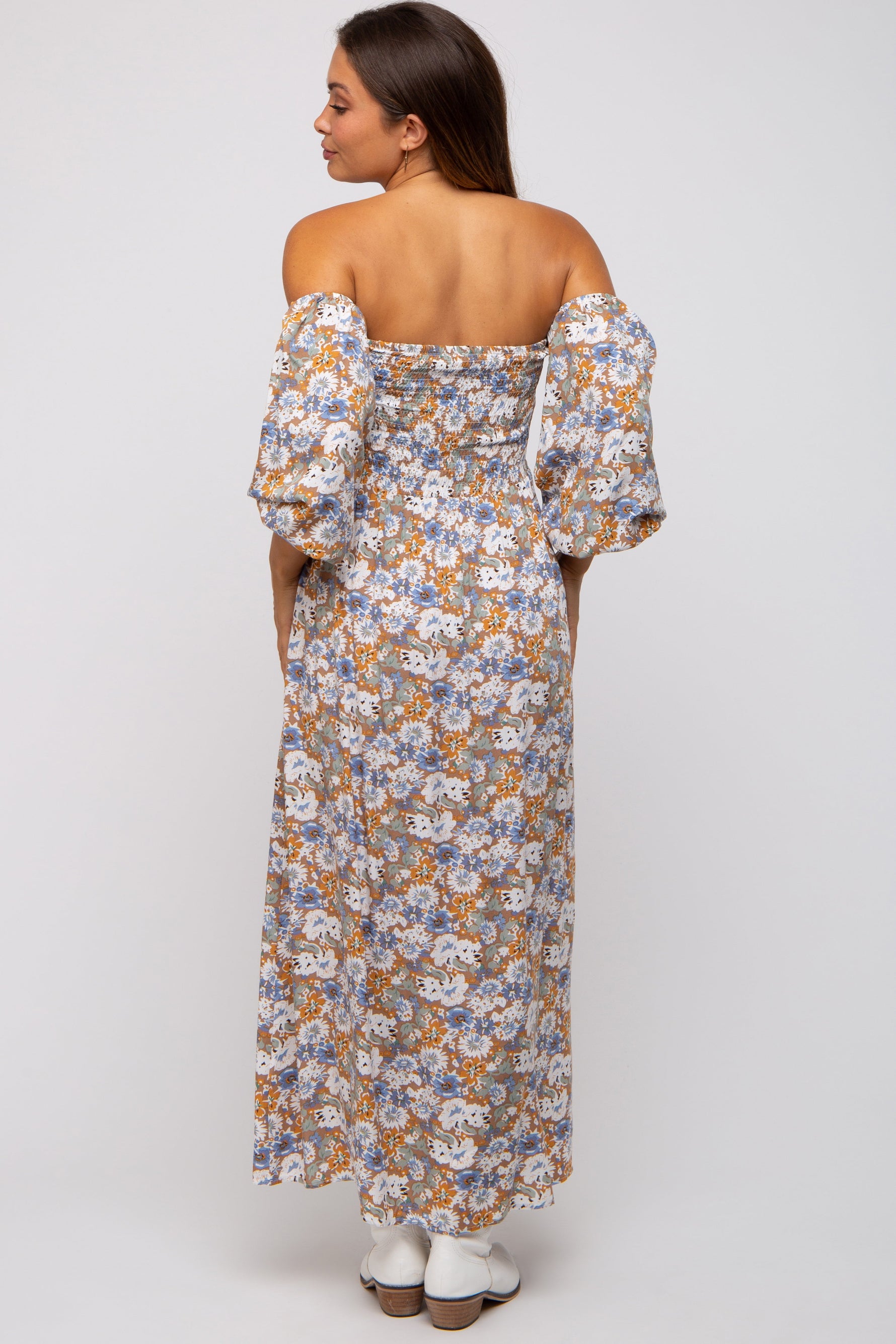 Pregnant woman wearing a taupe floral print off-shoulder smocked maternity maxi dress, smiling.