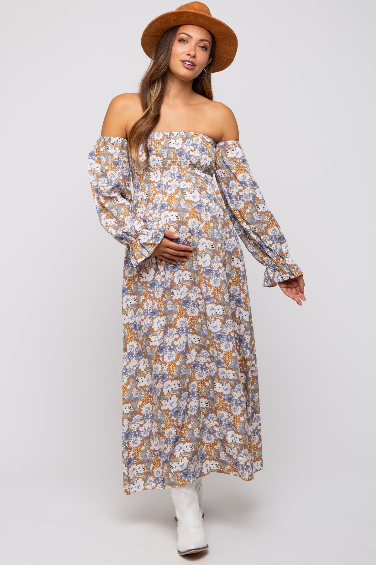 Pregnant woman wearing a taupe floral print off-shoulder smocked maternity maxi dress, smiling.