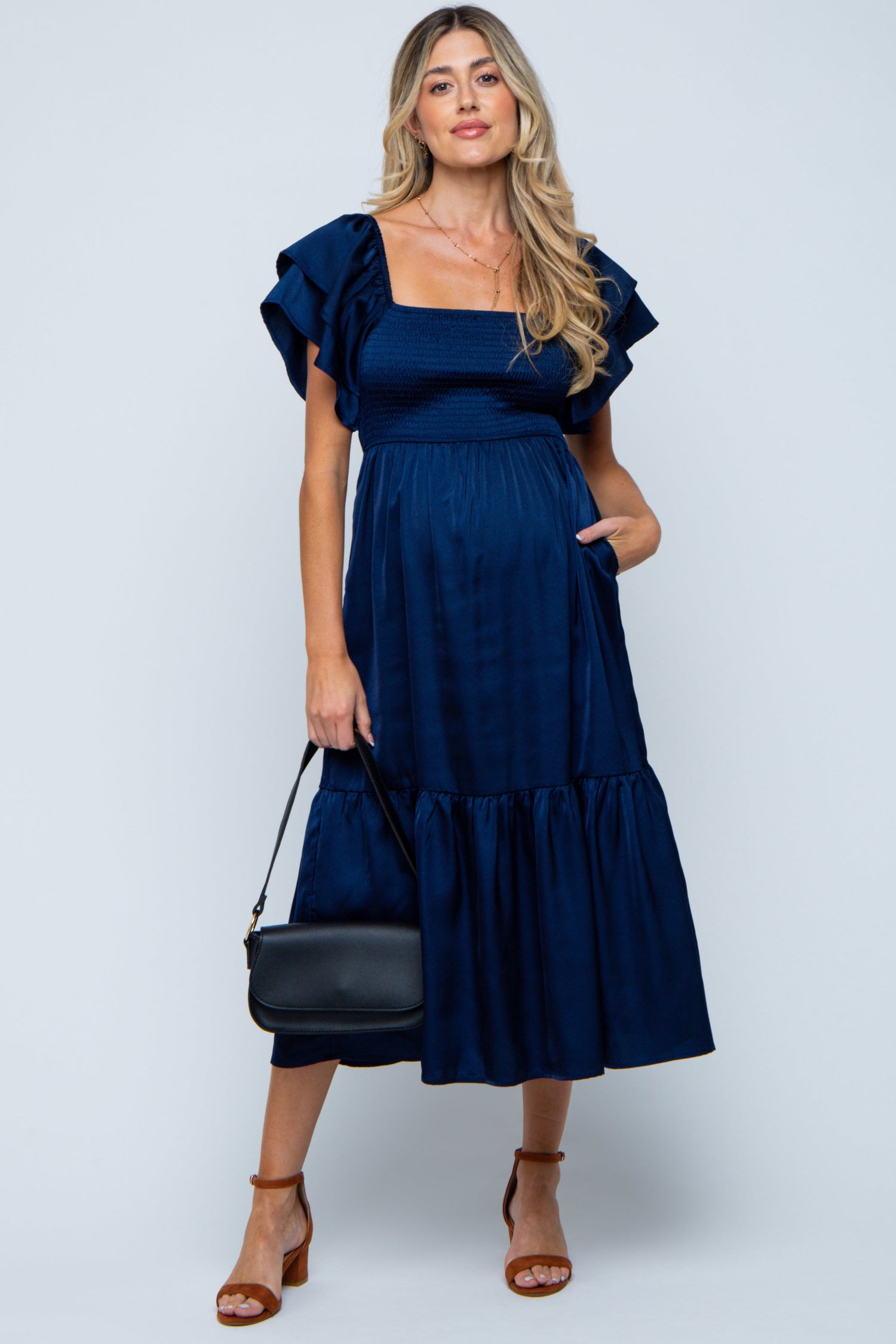 Navy satin maternity midi dress with flutter sleeves and an empire waist worn by a pregnant woman