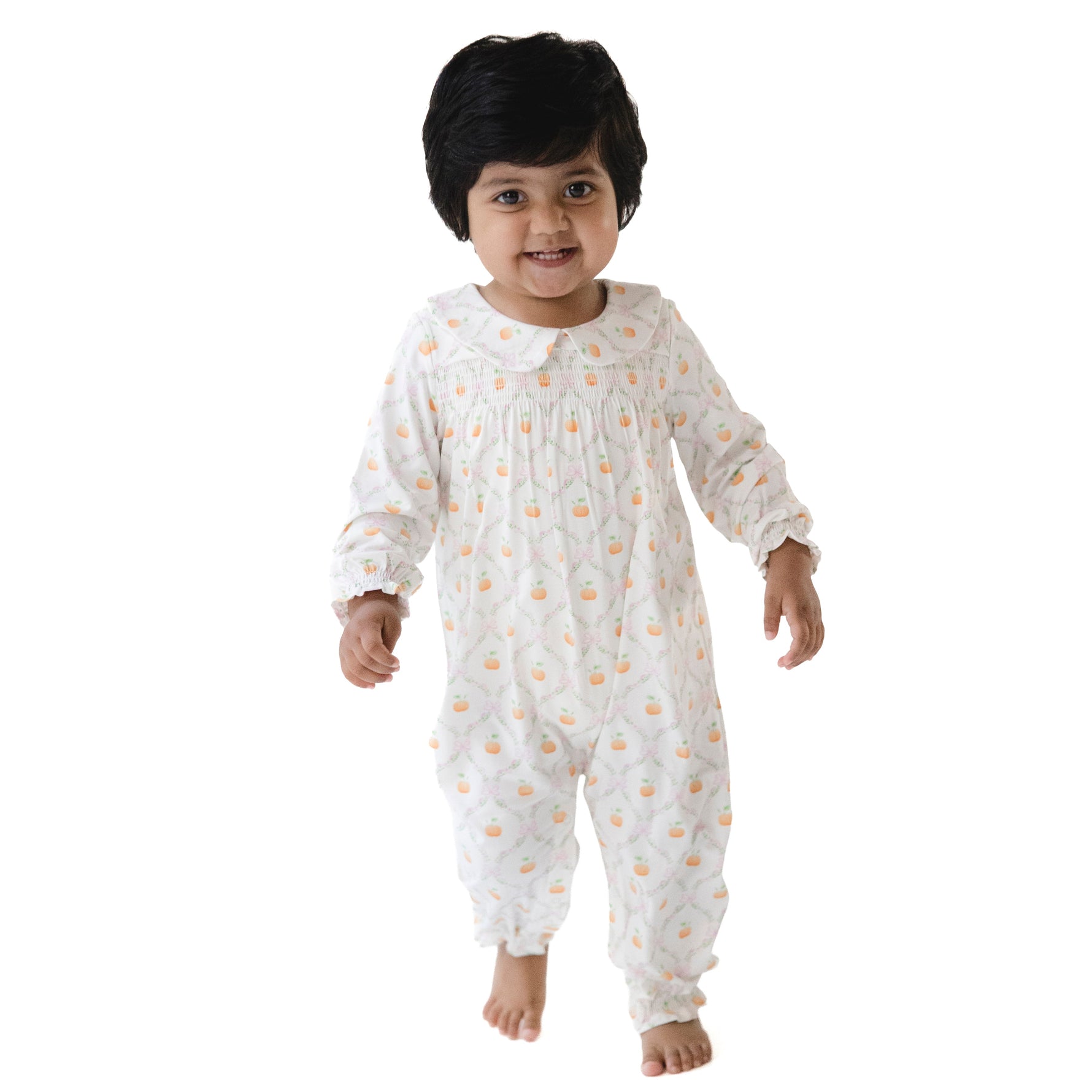 Long sleeve baby romper in an orange pumpkin trellis print with smocking across the chest and a white Peter Pan collar