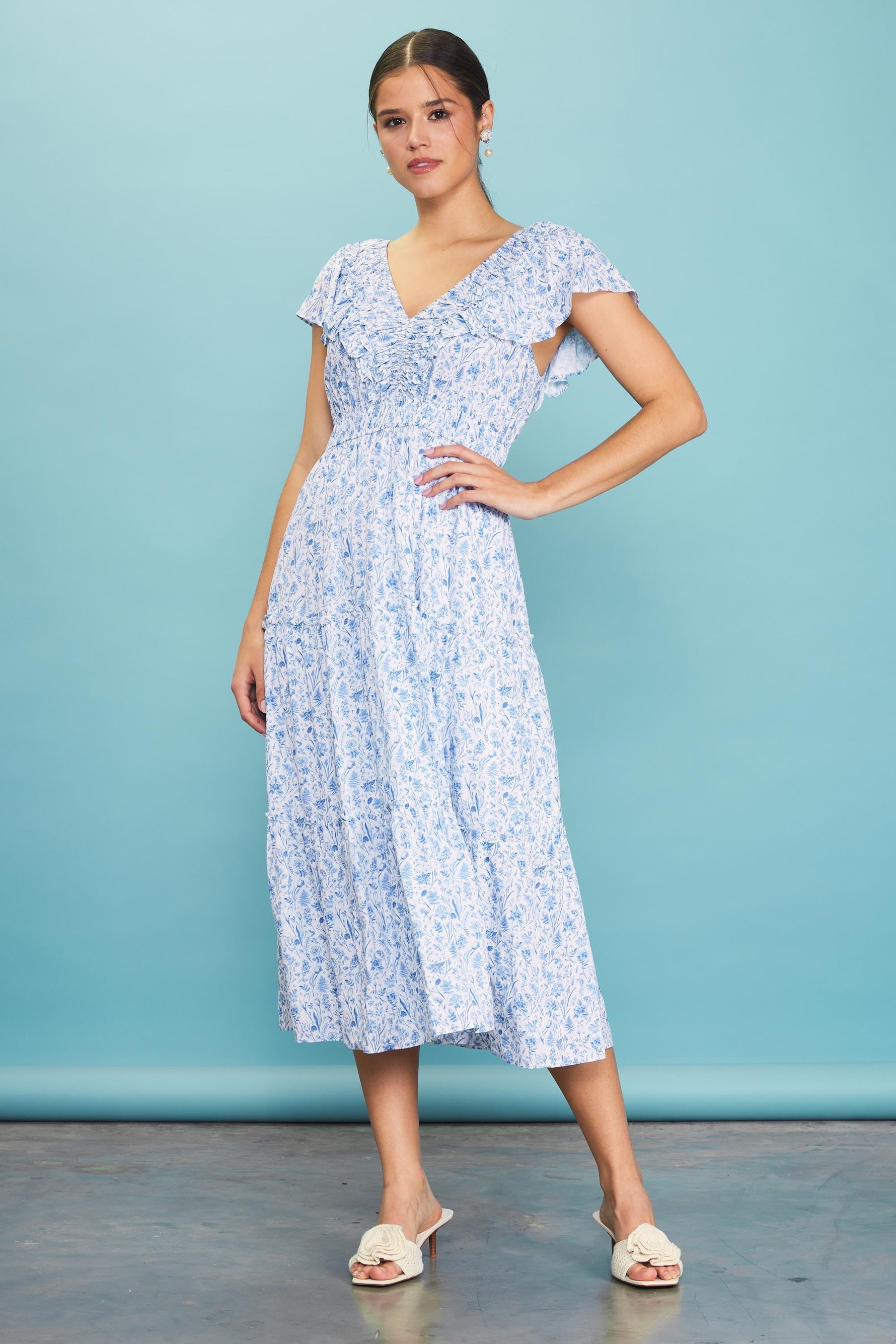 Blue floral midi dress with v-neckline, front ruching, flutter sleeves, and a ruffle-trimmed tiered A-line skirt