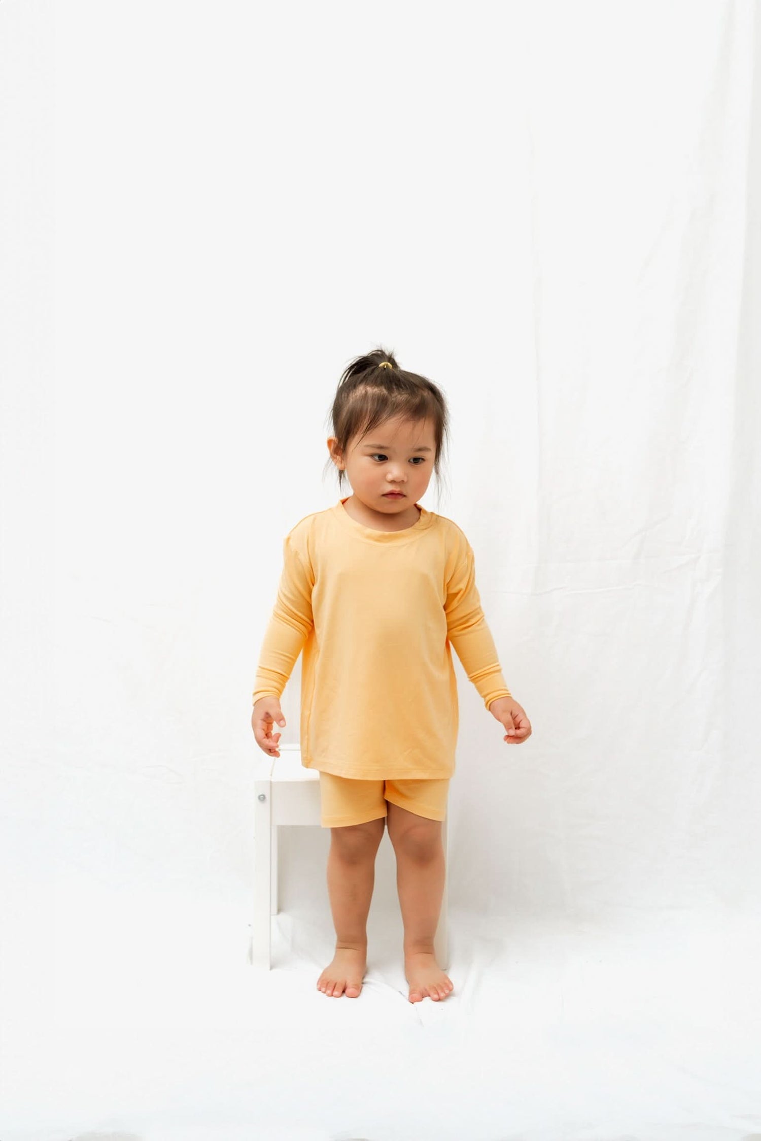 Children's papaya-colored biker short set with an oversized long sleeve top and matching shorts.