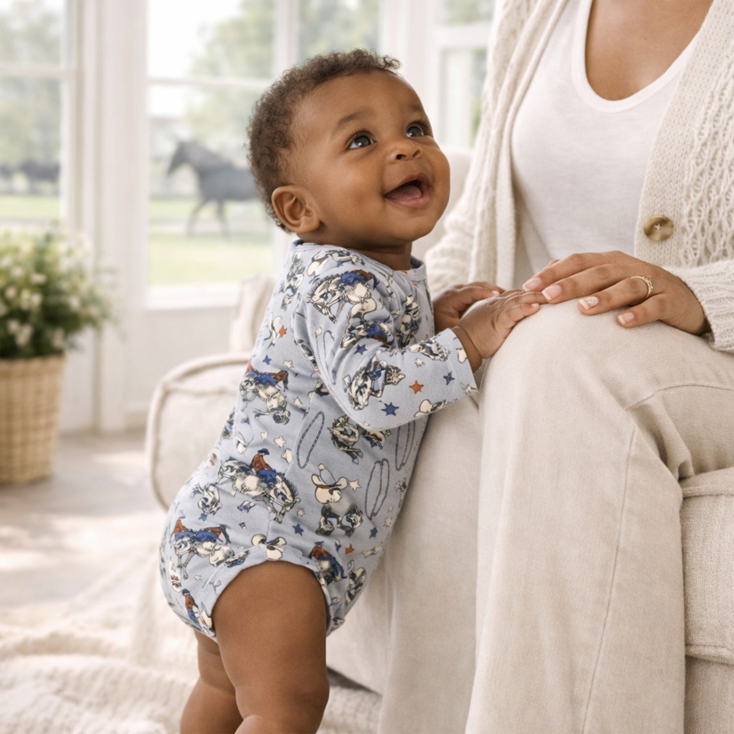 Baby bodysuit with a Western cowboy rodeo print, envelope neckline, and snap closures at the bottom.