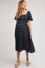 Navy floral square neck maternity midi dress with short sleeves and a smocked bodice.