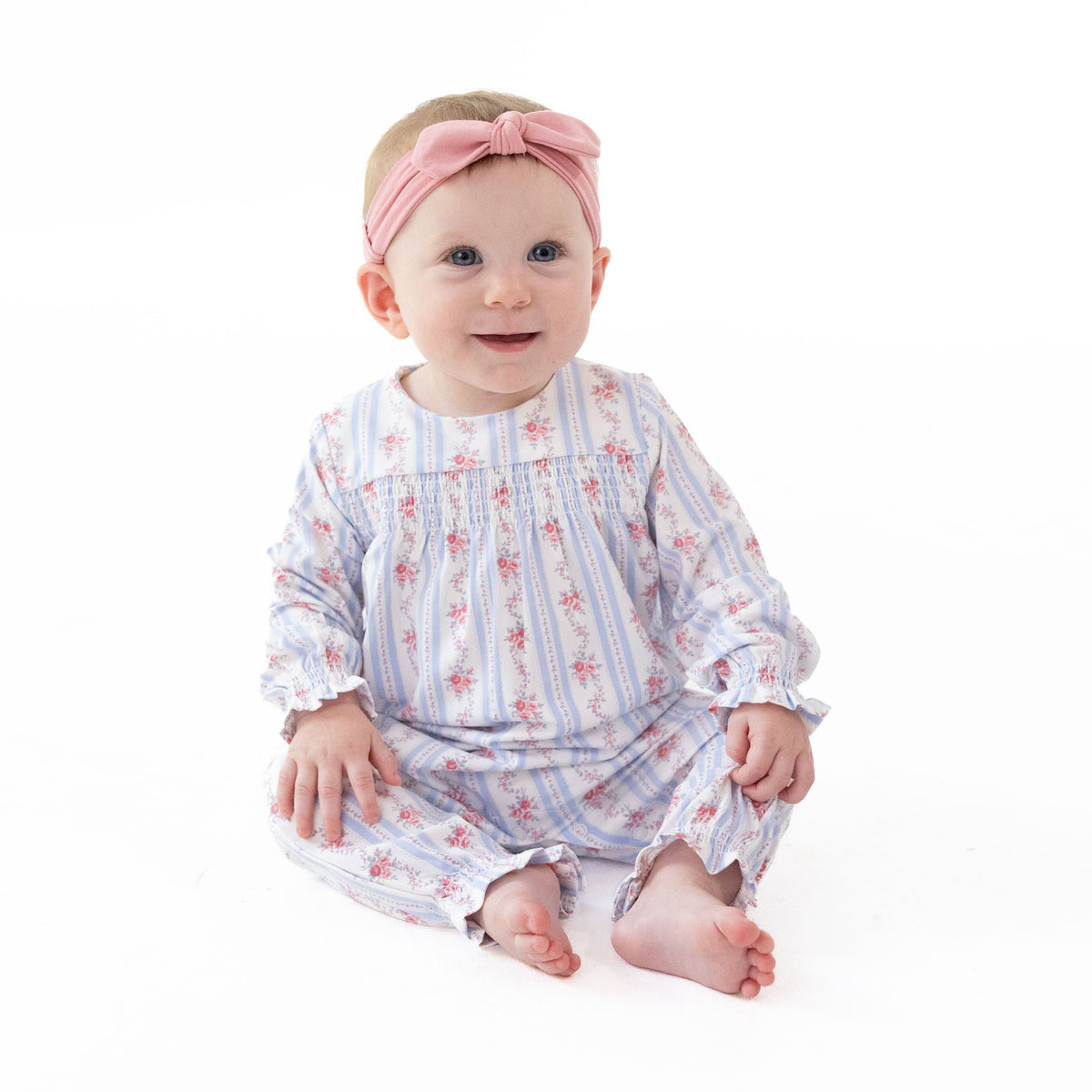 Long sleeve baby romper in a floral stripe print with smocked detailing across the chest