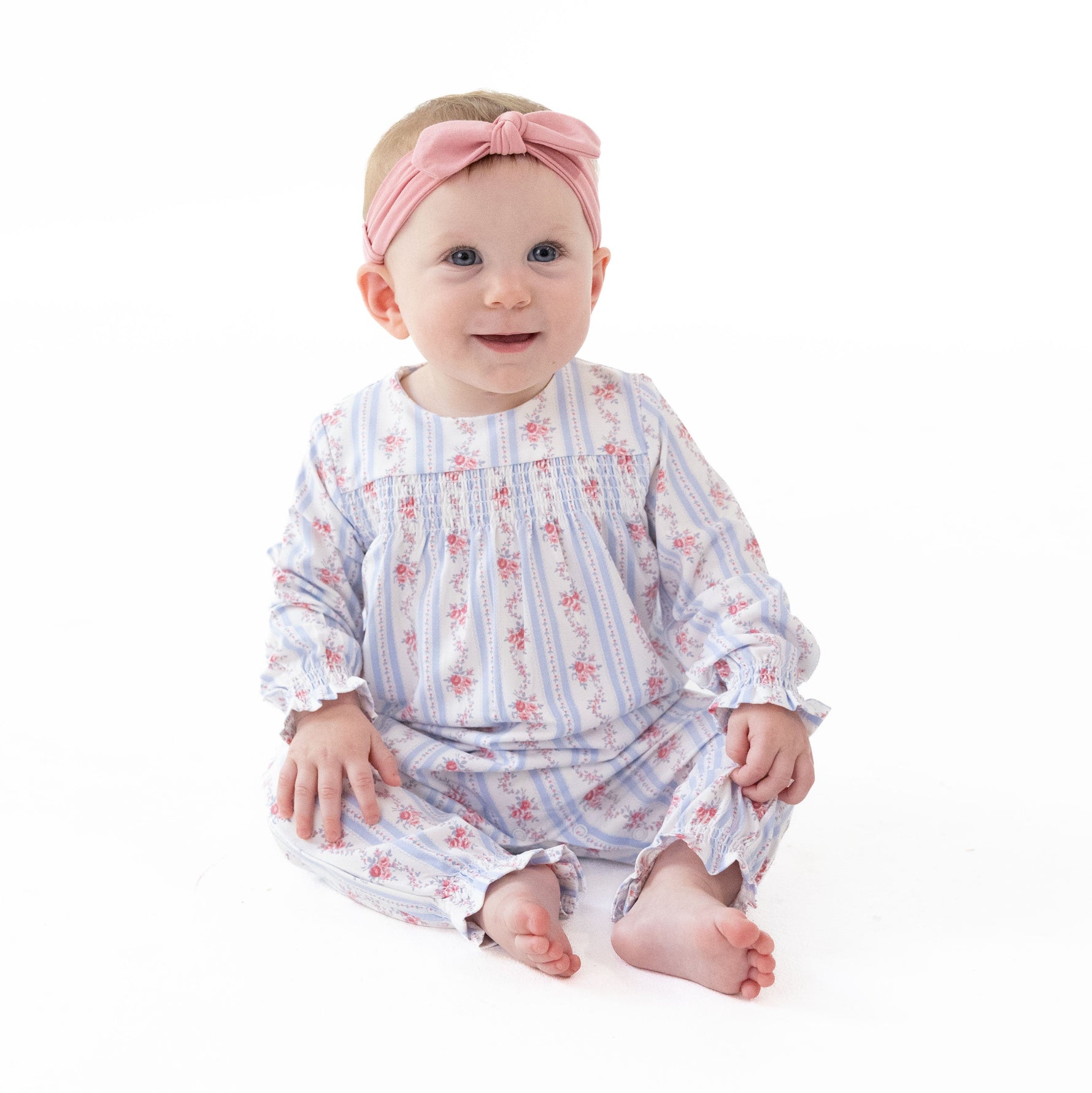 Long sleeve baby romper in a floral stripe print with smocked detailing across the chest