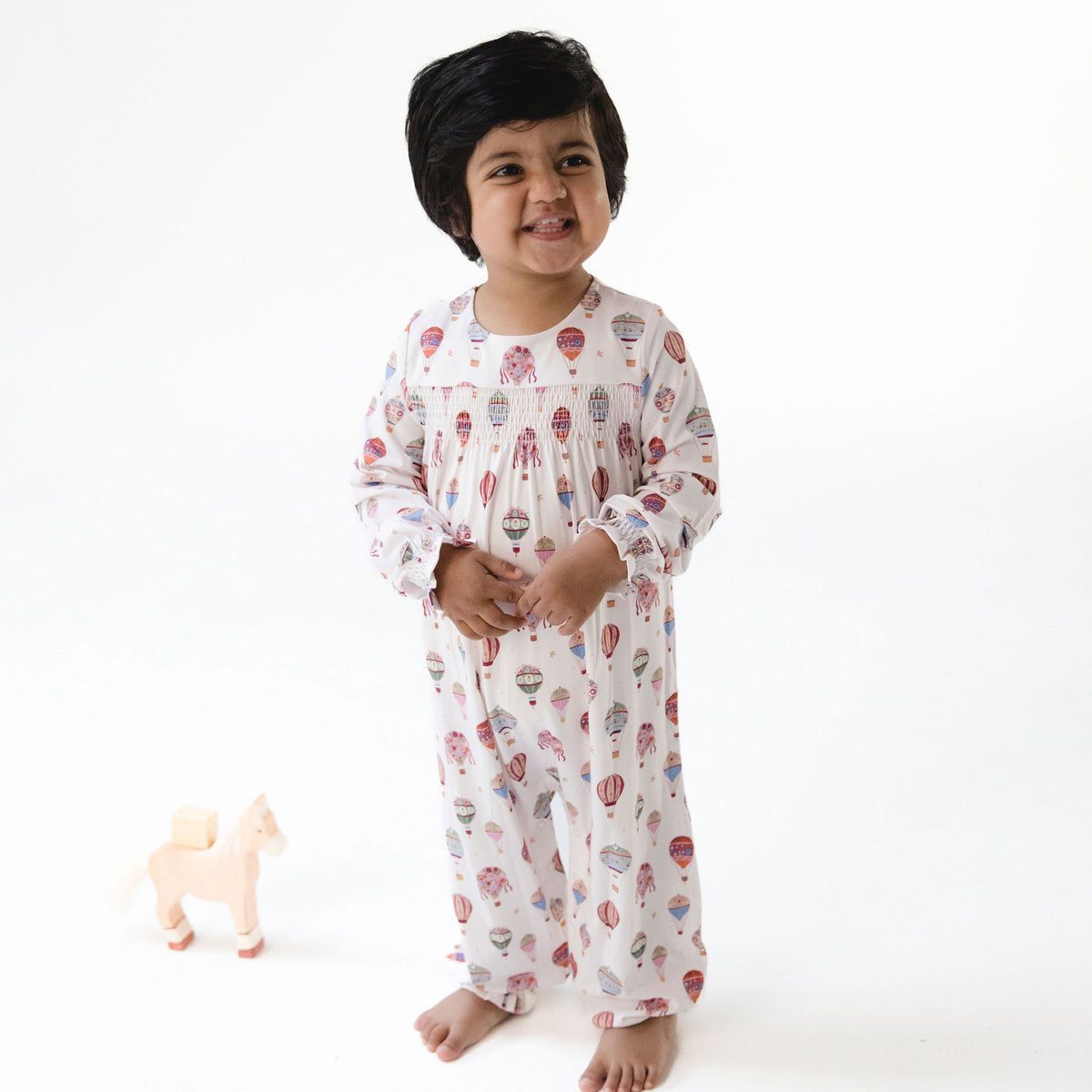 Long sleeve baby romper with hot air balloon print and smocked detail across the chest