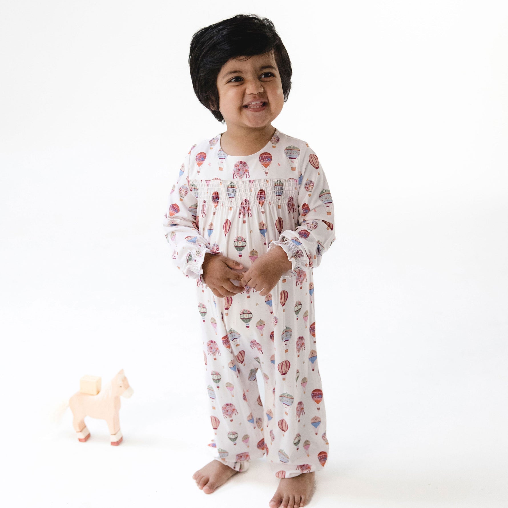 Long sleeve baby romper with hot air balloon print and smocked detail across the chest