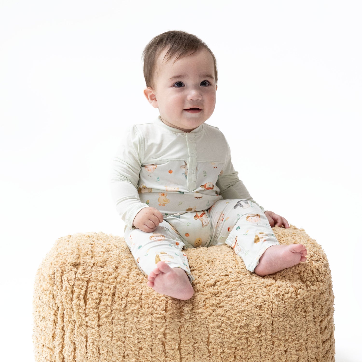 Baby romper with a farm faces print body and contrasting-colored long sleeves, with snap closures at the bottom.