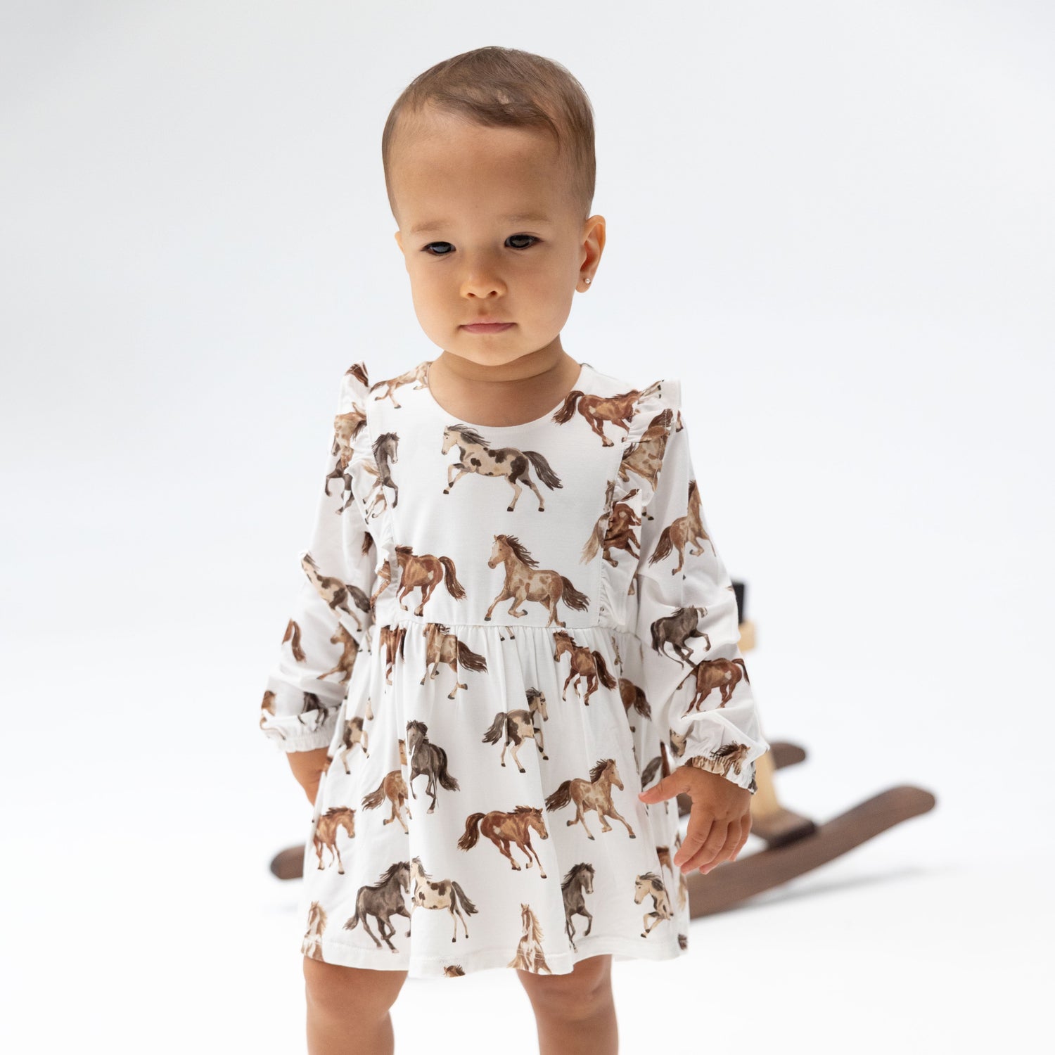 Long sleeve ruffle bodysuit dress in a wild horses print with a snap bottom.