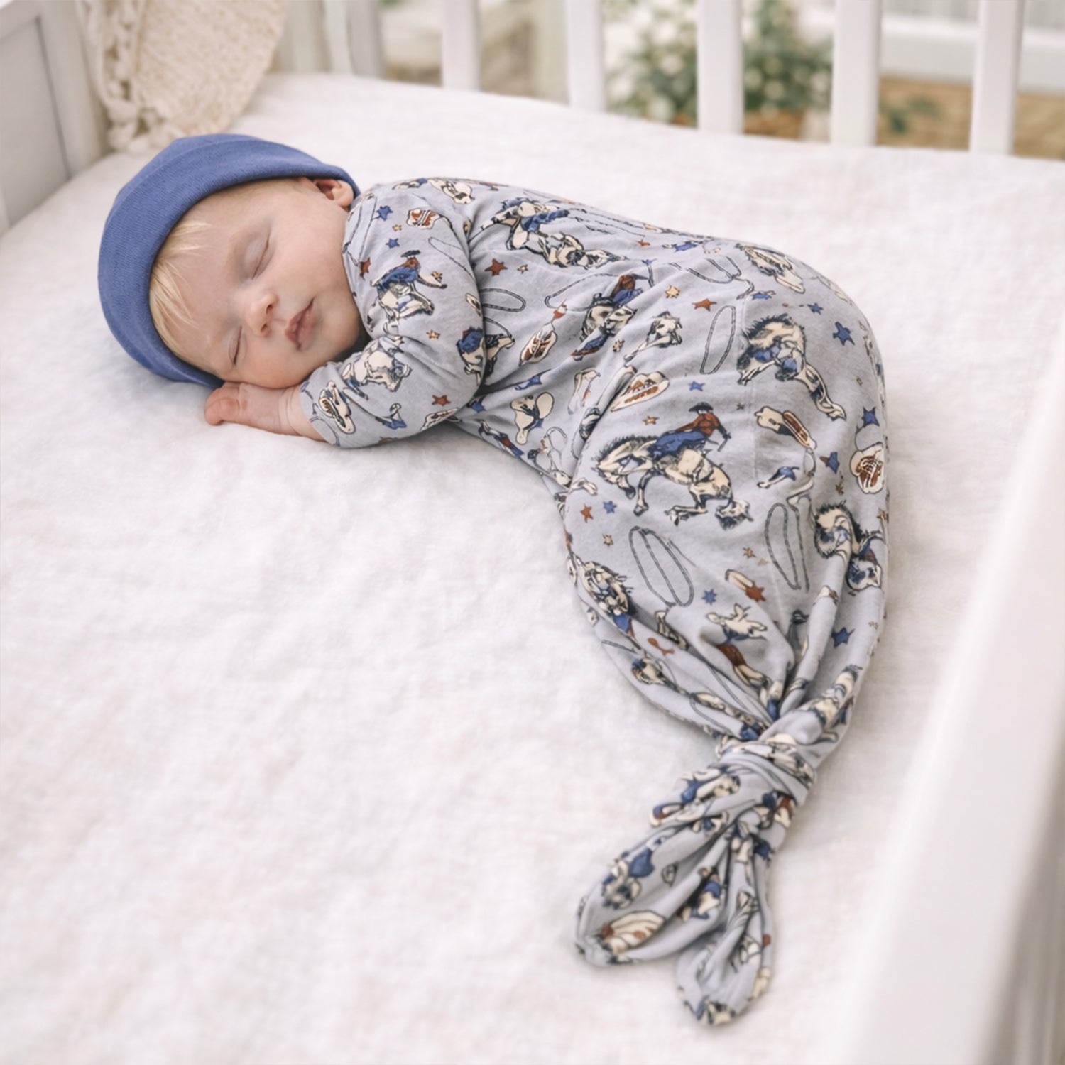 Baby gown with a Western cowboy print of broncos, boots, and lassos, featuring an envelope neckline and knot-tie bottom.
