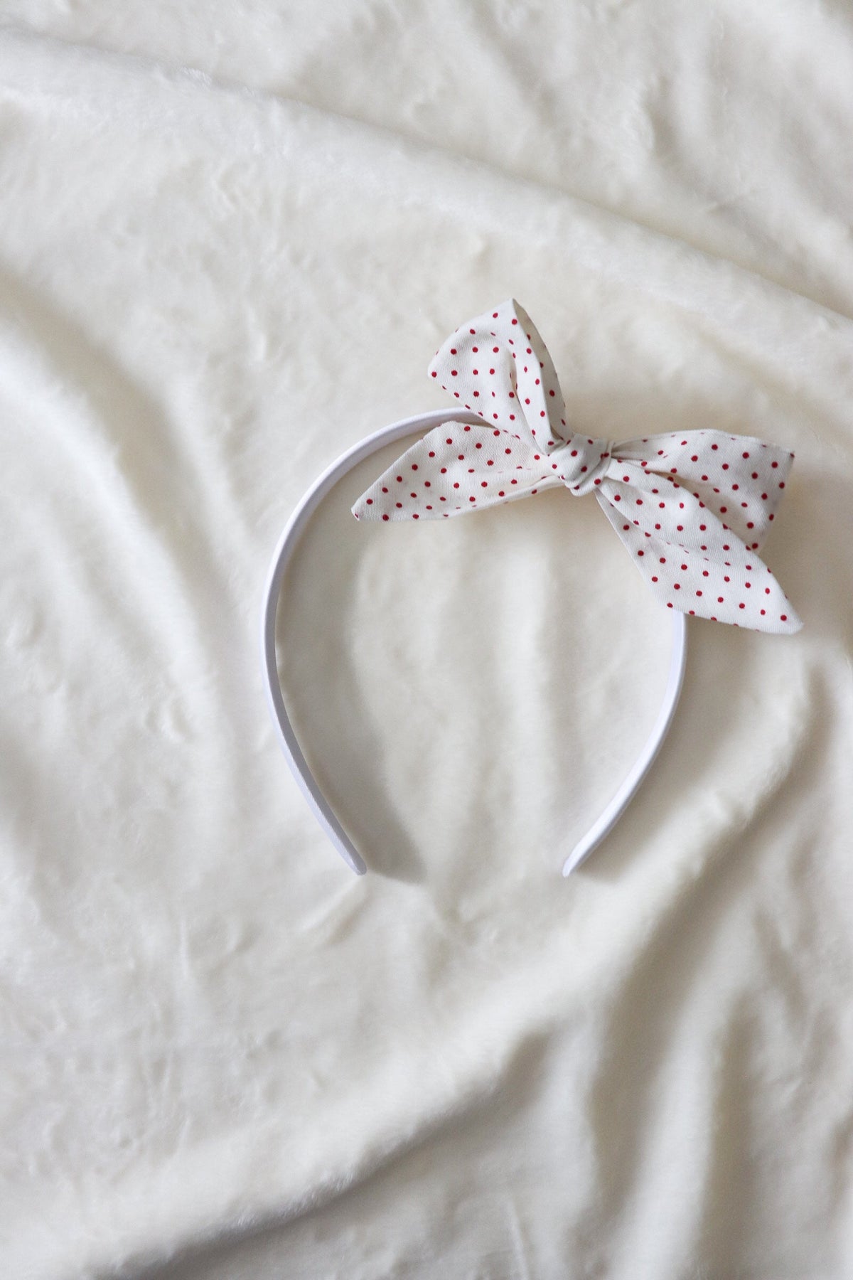 Close-up of a baby wearing a soft ruby red knit headband by Little Mae & Co, on a light background.