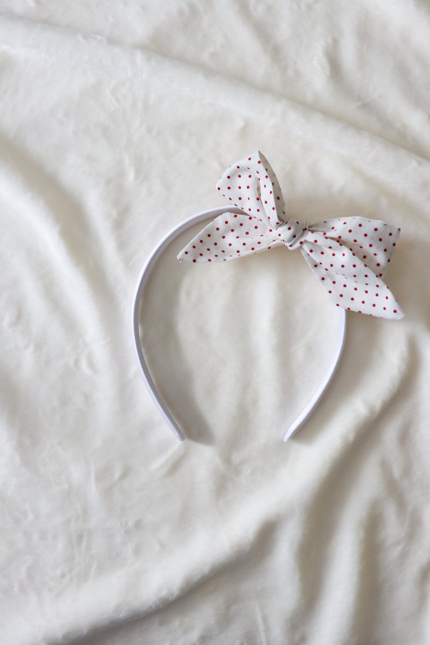 Close-up of a baby wearing a soft ruby red knit headband by Little Mae & Co, on a light background.
