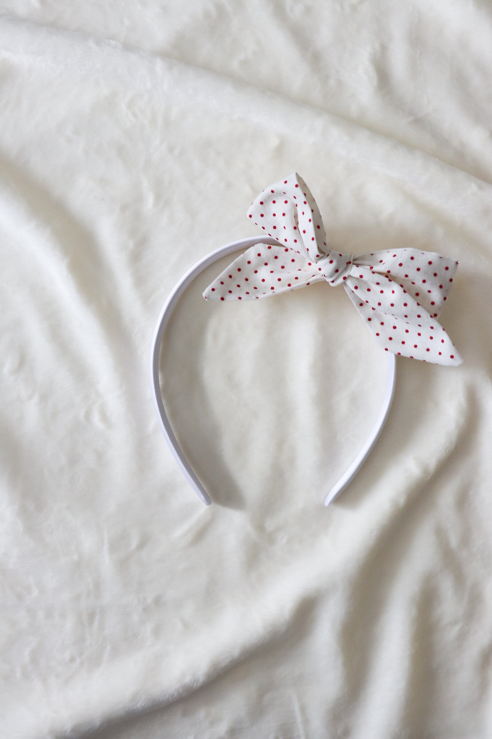 Close-up of a baby wearing a soft ruby red knit headband by Little Mae & Co, on a light background.