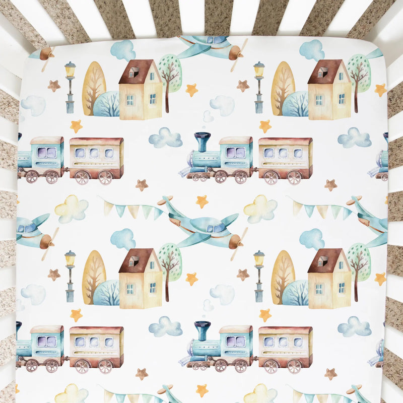 Fitted crib sheet with airplane and train design on a standard crib mattress.