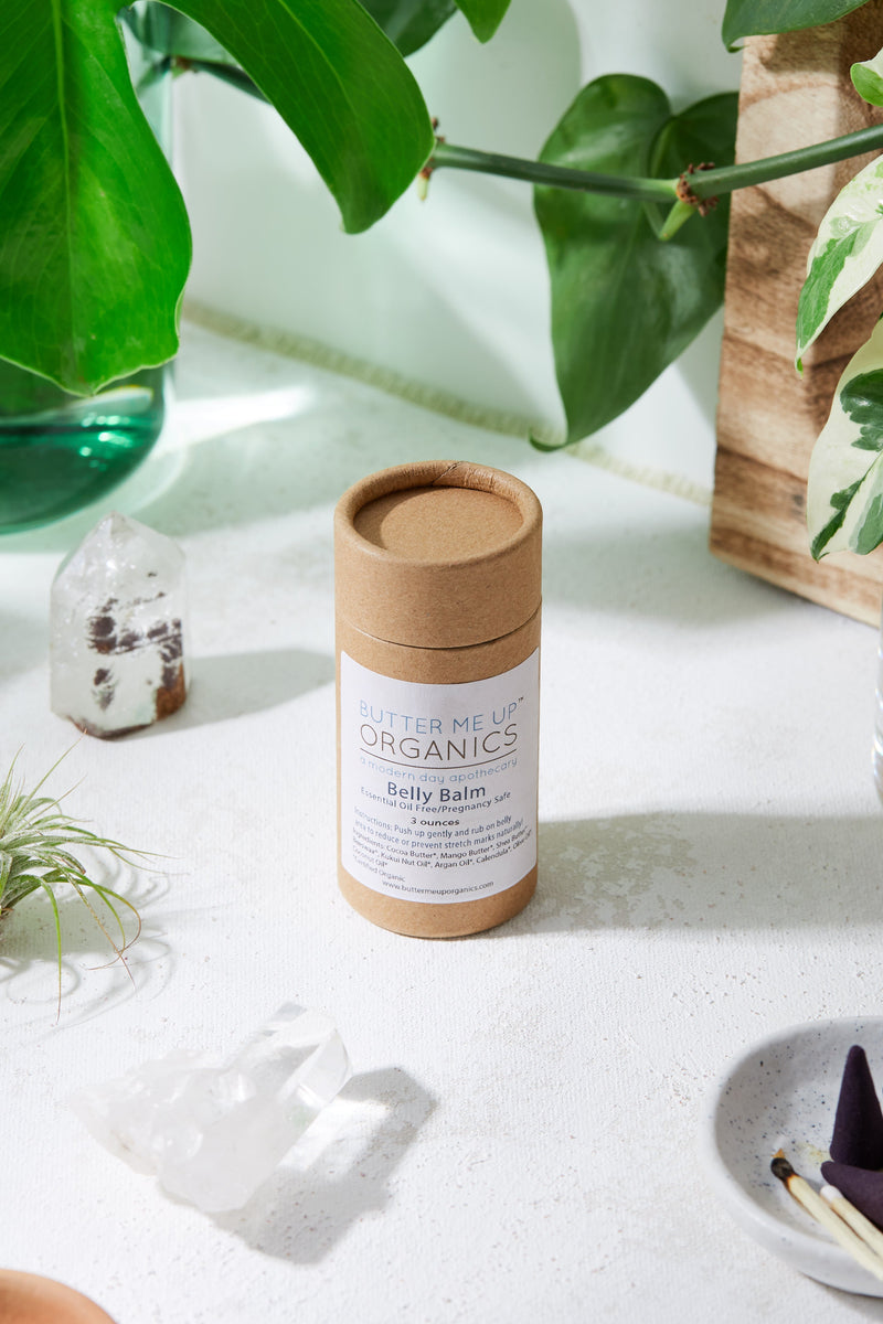 Organic Pregnancy Balm in compostable tube amidst plants, designed to prevent stretch marks.