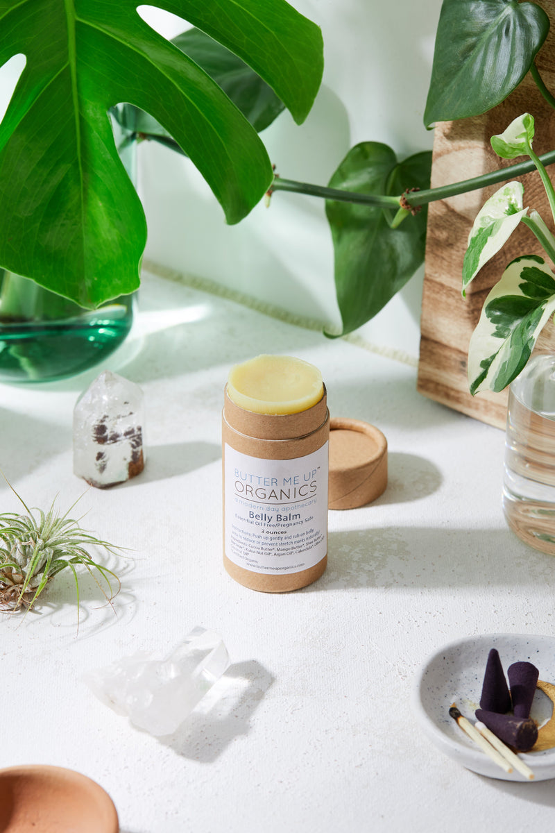 Organic Pregnancy Balm in eco-friendly tube, surrounded by plants and crystals.