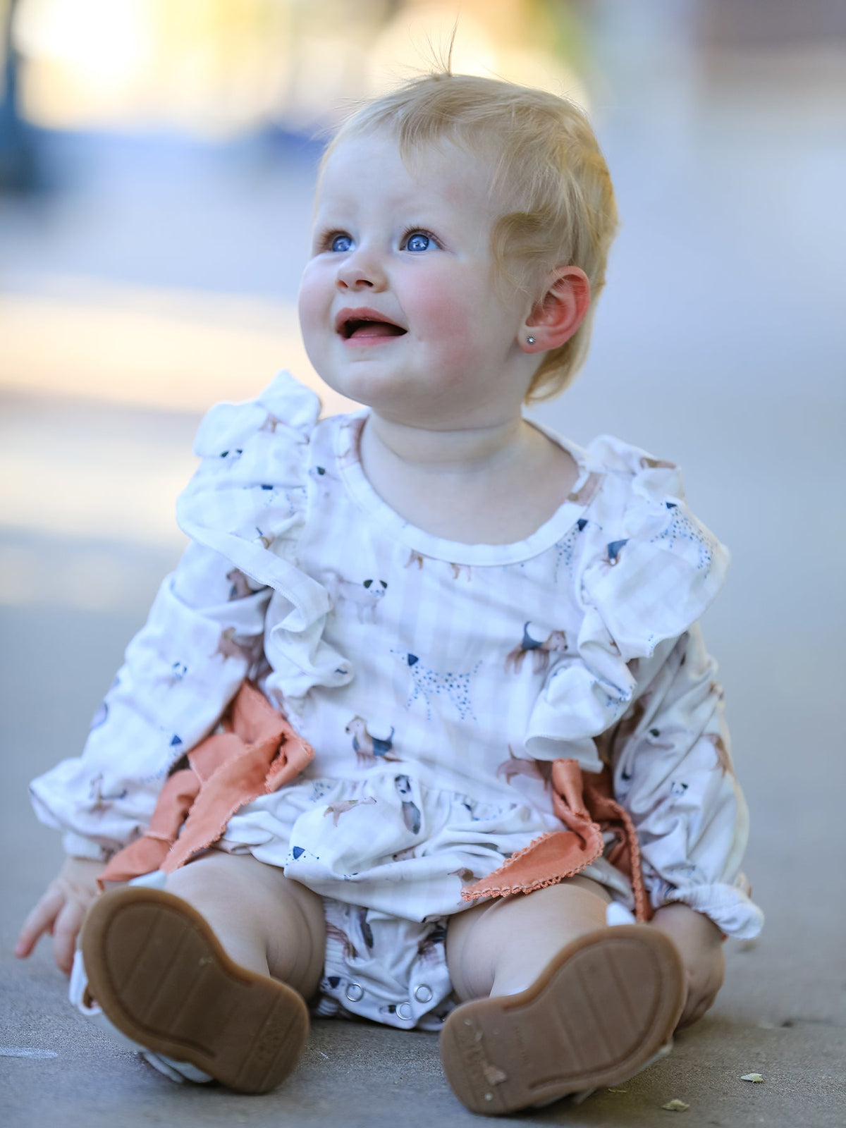 Long sleeve baby romper in fall plaid with a dog print, finished with bow and ruffle accents