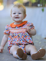 Bubble romper in a fall floral print with puff sleeves, smocked embroidery detail, and a contrasting petal collar