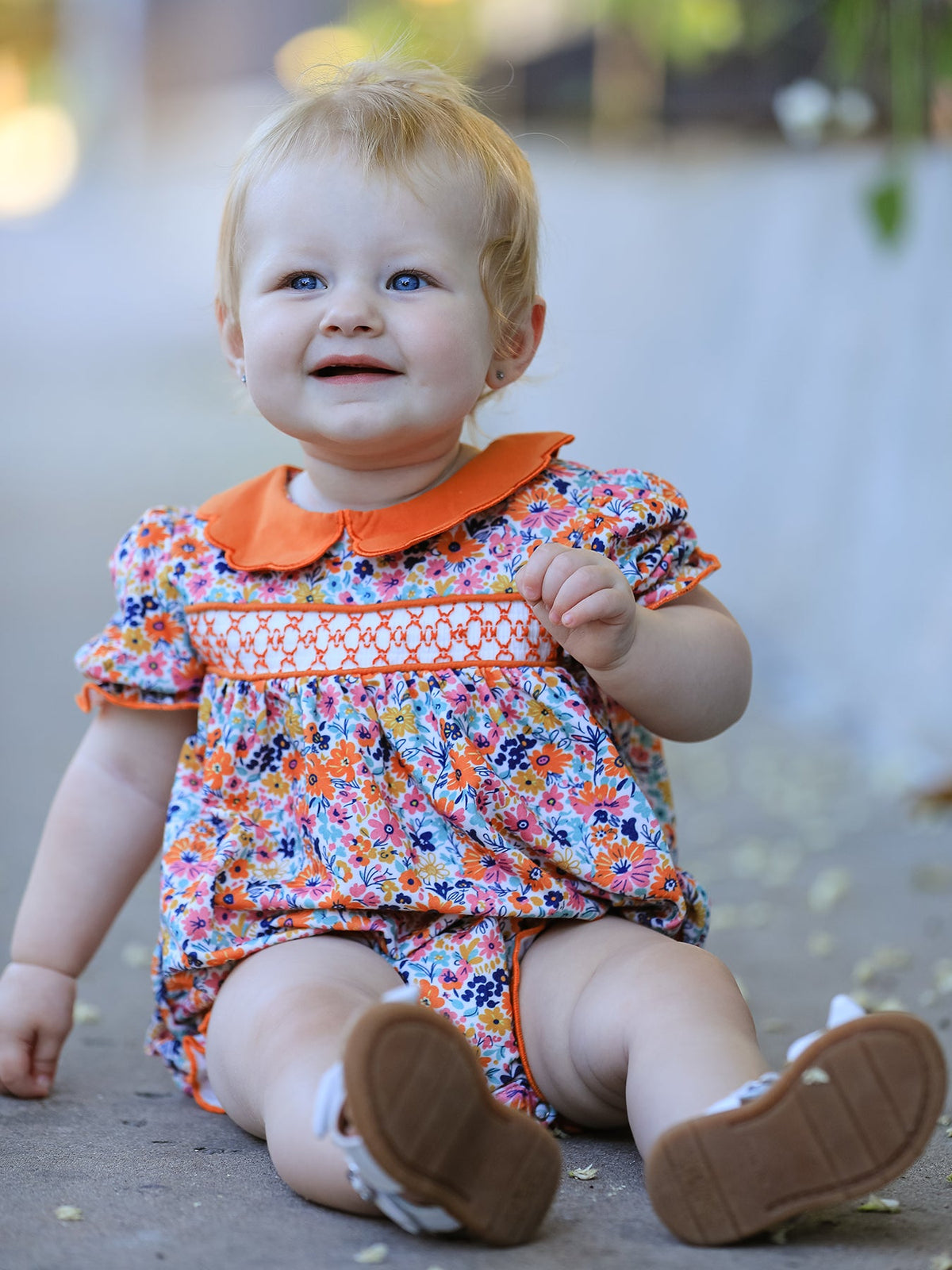 Bubble romper in a fall floral print with puff sleeves, smocked embroidery detail, and a contrasting petal collar