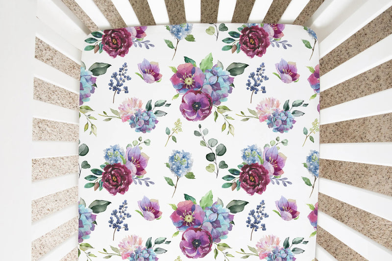 Fitted crib sheet with blue floral design in a crib.