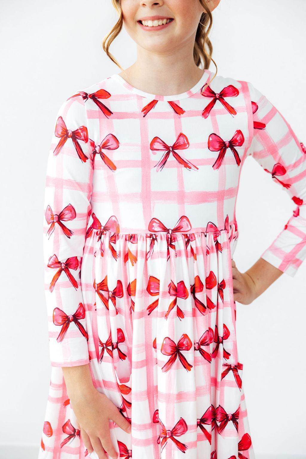 Long sleeve twirl dress with a bow print, full-circle skirt, pockets, and scoop back neckline