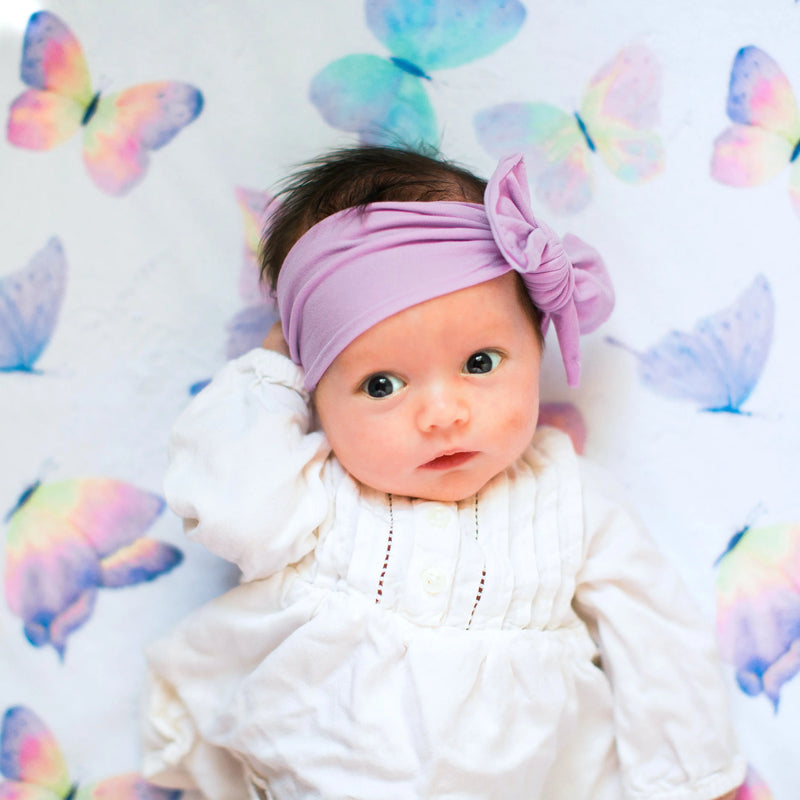 Baby lying on a premium butterfly-themed blanket, showcasing vibrant colors and minky dot texture for sensory stimulation.