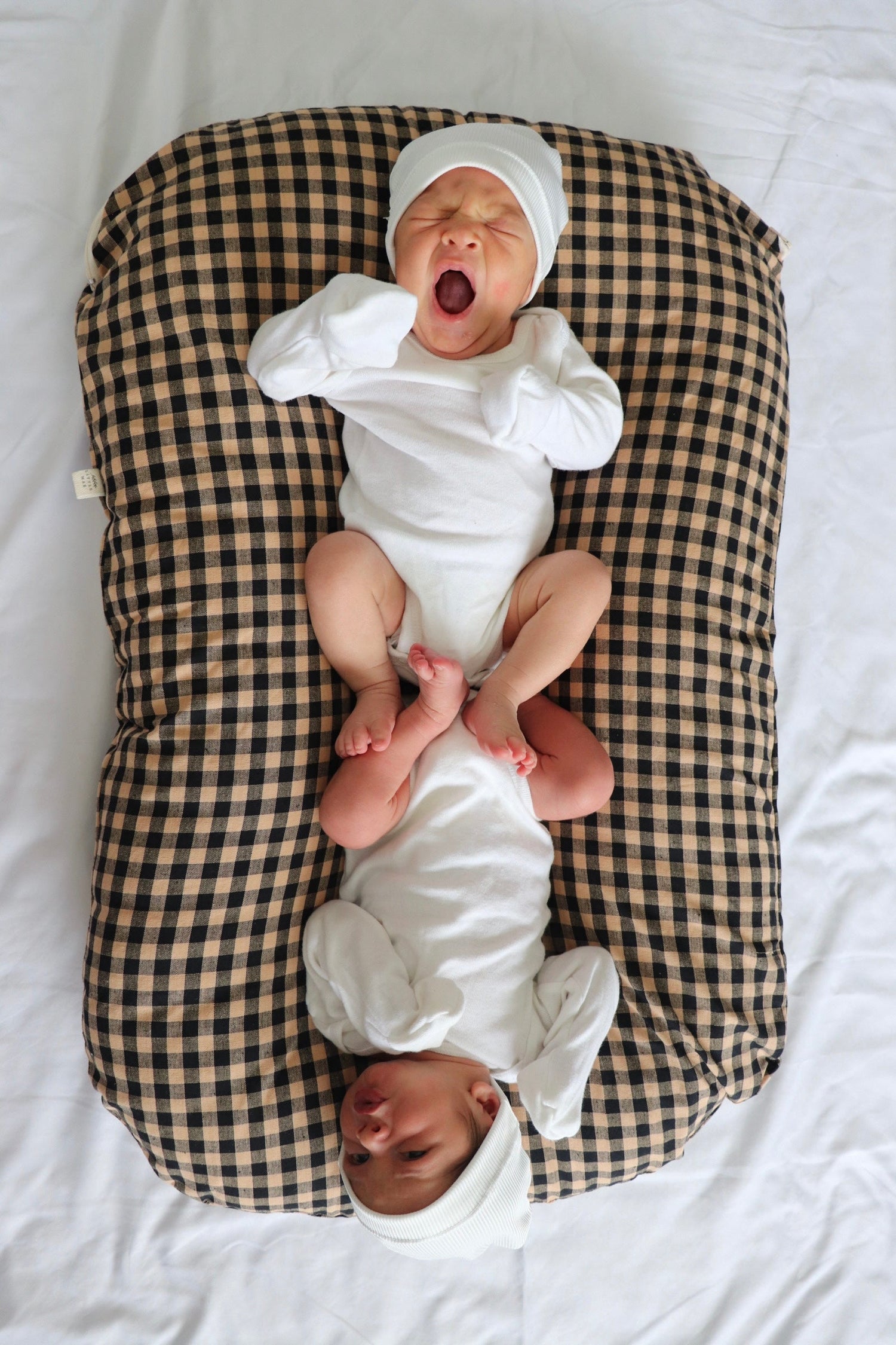 Baby lounger cover in brown and black gingham with a ruffle-trimmed top edge.