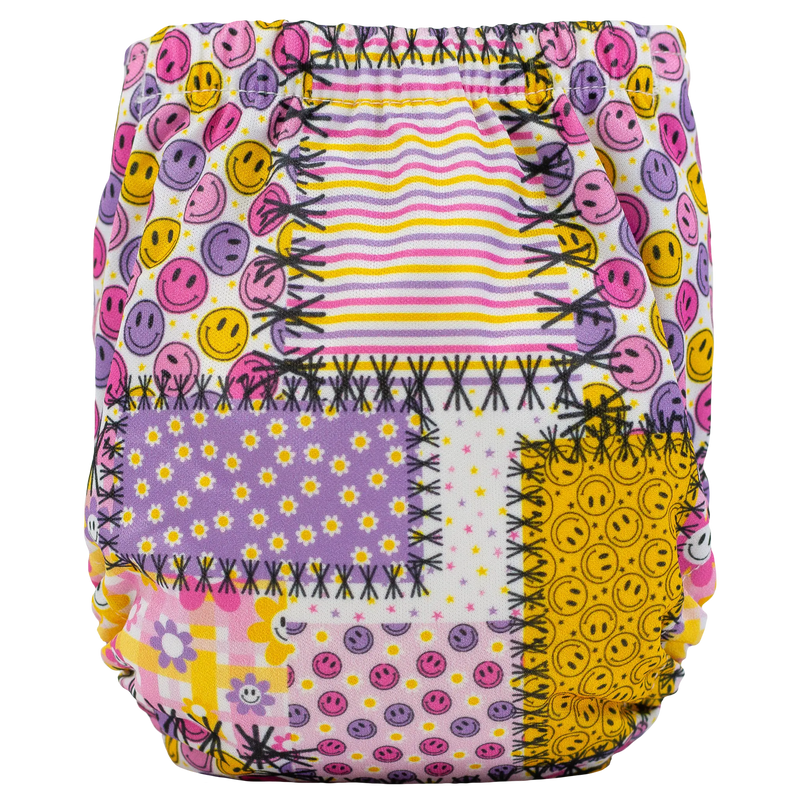 Tiny Tushies Newborn AIO Cloth Diaper with colorful smiley face and patchwork pattern.
