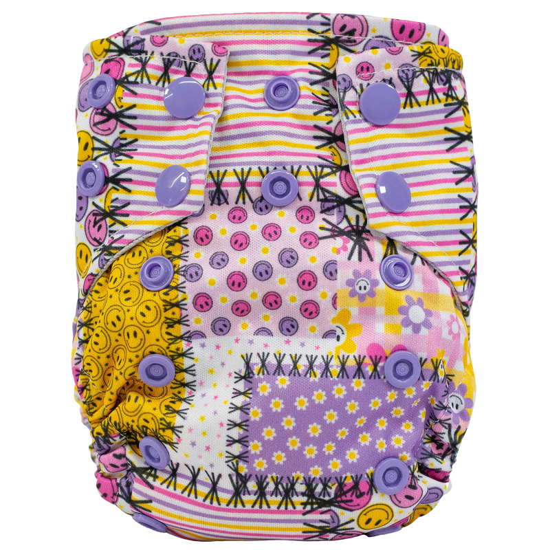 Tiny Tushies Newborn AIO Cloth Diaper with colorful patchwork design and purple snaps.