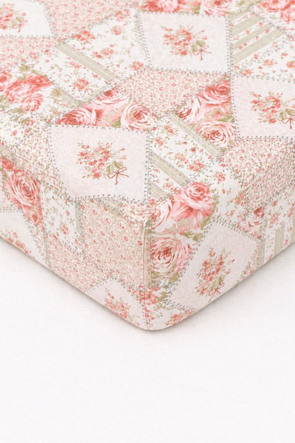 Crib sheet with pink and green toile patch print fitted over a standard crib mattress.