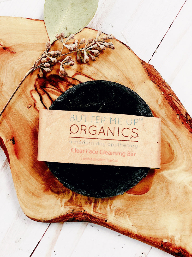 Organic activated charcoal face soap on wooden tray, natural skincare product.