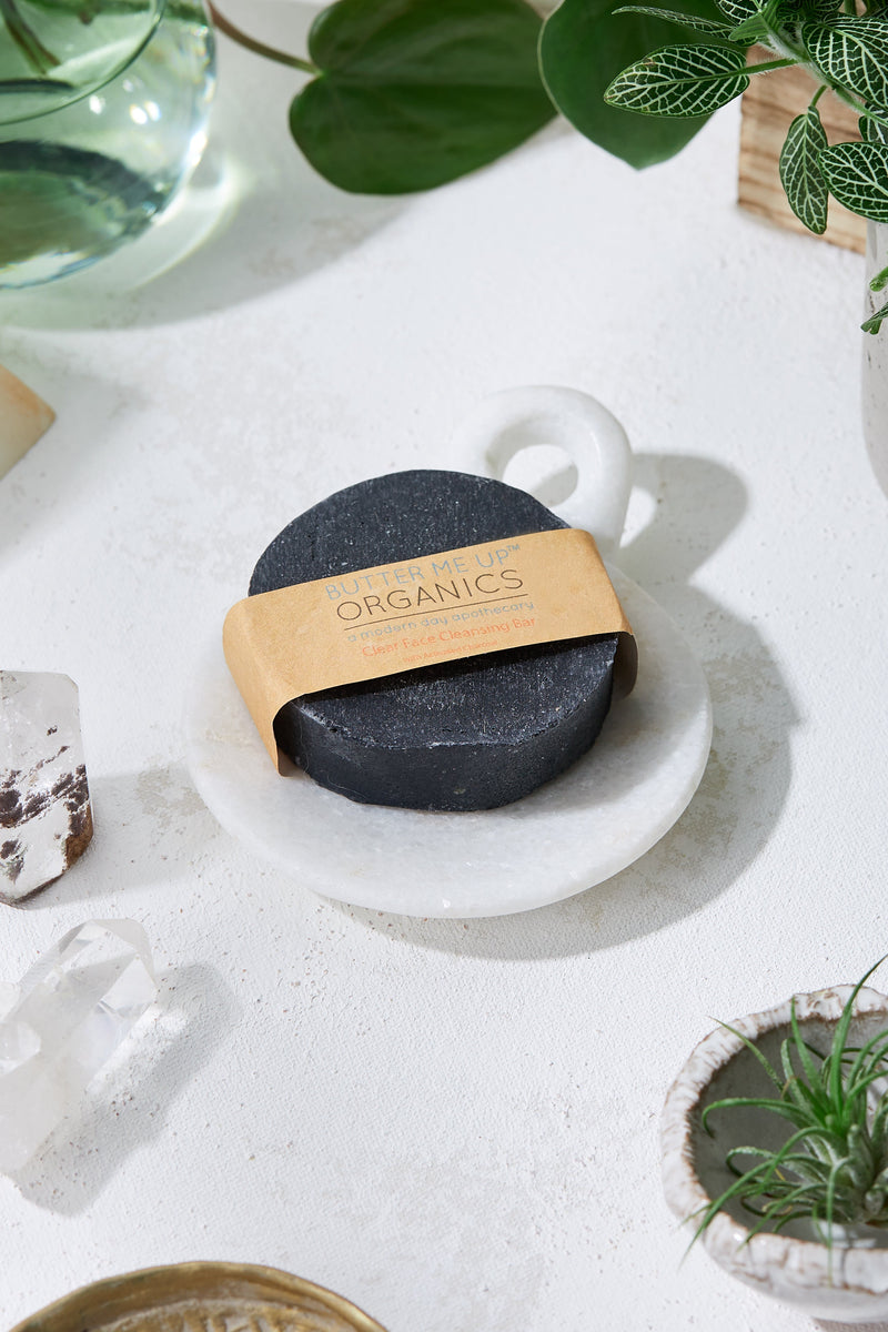 Organic activated charcoal face wash soap on a marble dish.