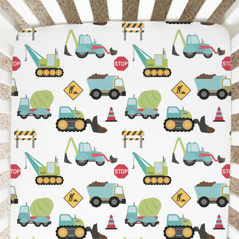 Fitted crib sheet with construction truck pattern in a crib.