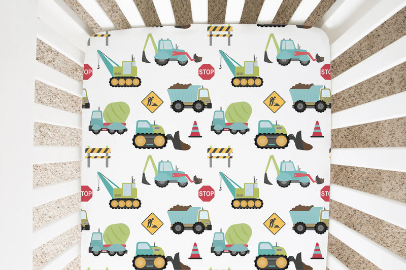 Fitted crib sheet with construction trucks pattern in a crib.