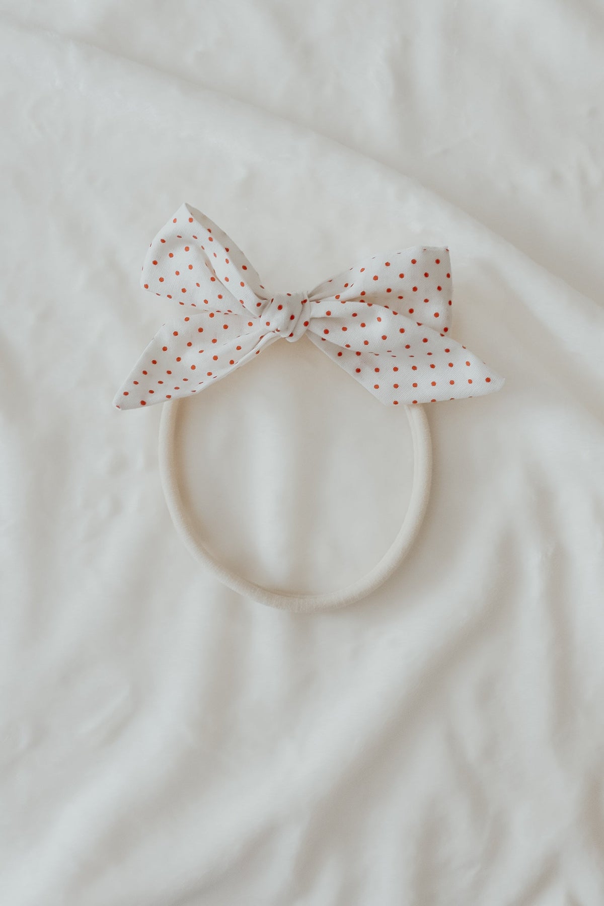 Close-up of a baby wearing a soft ruby red knit headband by Little Mae & Co, on a light background.