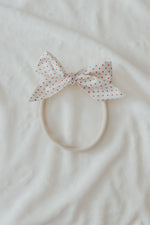 Close-up of a baby wearing a soft ruby red knit headband by Little Mae & Co, on a light background.