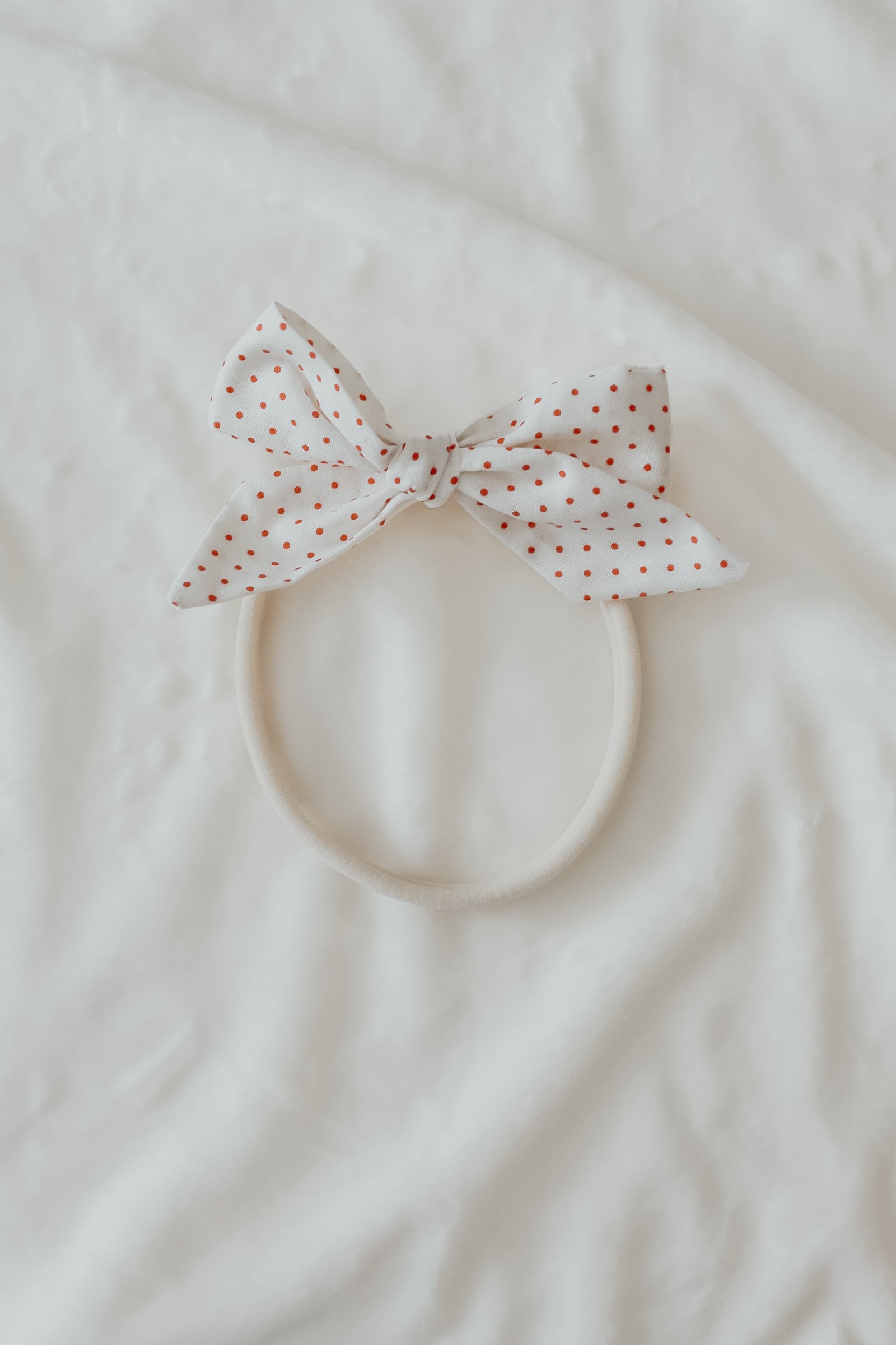 Close-up of a baby wearing a soft ruby red knit headband by Little Mae & Co, on a light background.