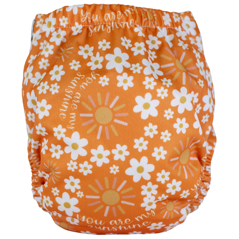 Tiny Tushies Newborn AIO Cloth Diaper with floral and sunshine print, featuring secure snaps and an adjustable fit.