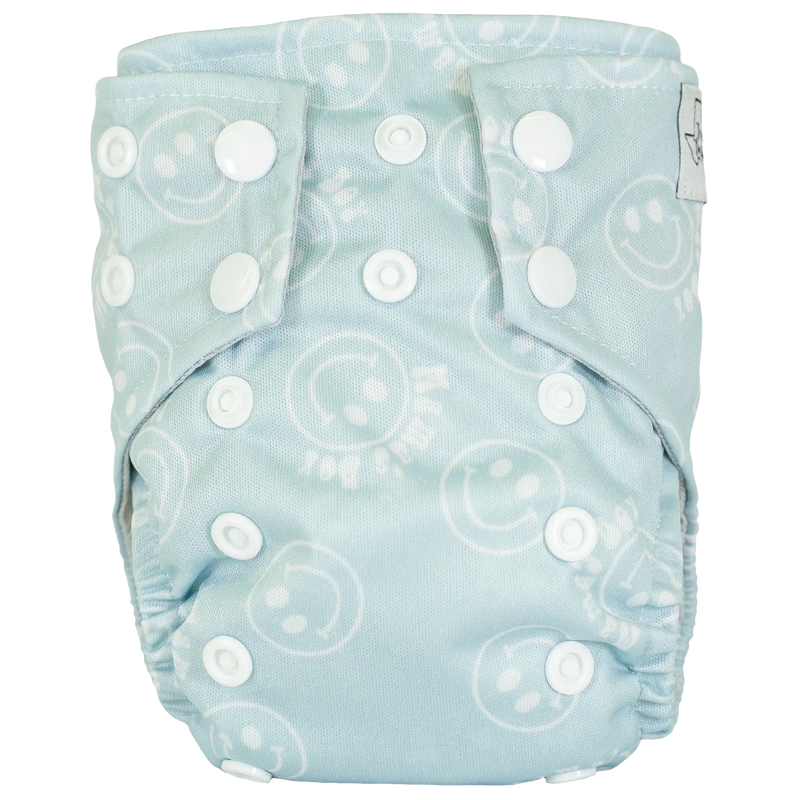 Tiny Tushies Newborn AIO cloth diaper with snaps and smiley face pattern.
