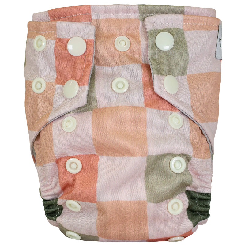 Tiny Tushies Newborn AIO Cloth Diaper with orange-green checkered pattern and secure snaps.