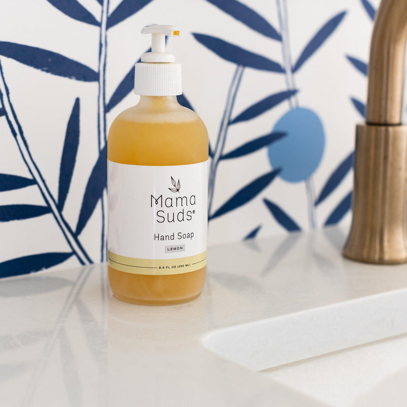 MamaSuds hand soap bottle on bathroom counter with floral background.
