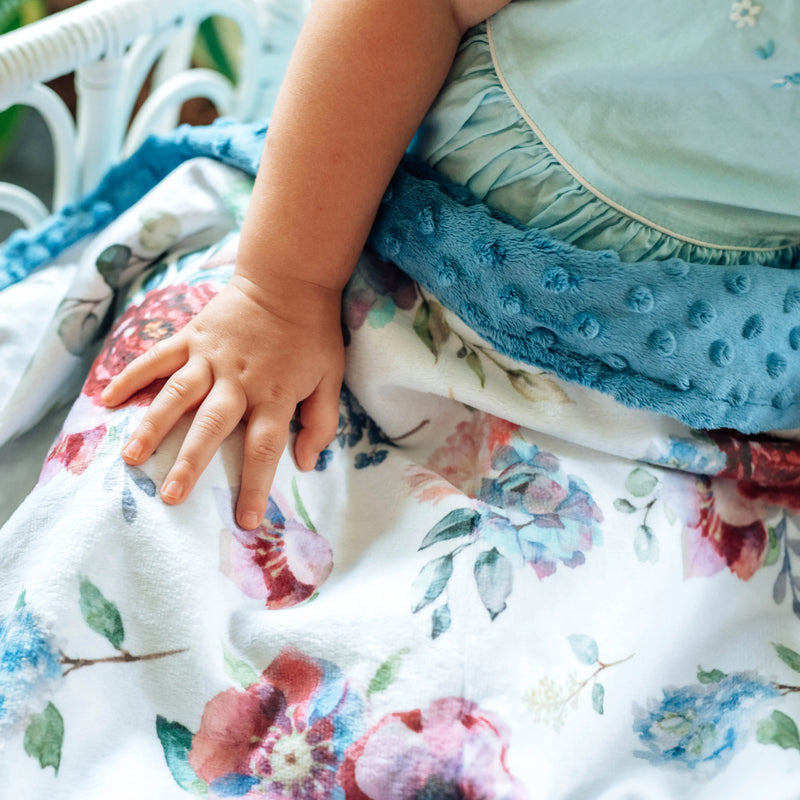 Baby wrapped in a blue floral minky blanket with soft texture.