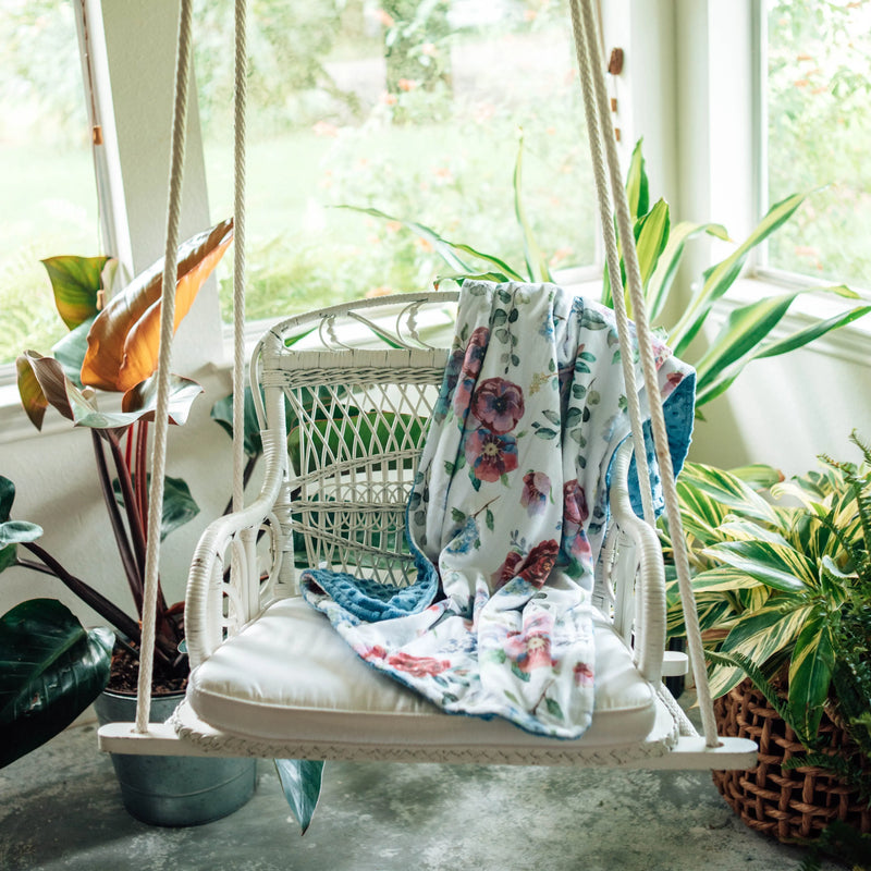 Blue floral baby and toddler minky blanket on a swing chair, showcasing soft texture and vibrant pattern.